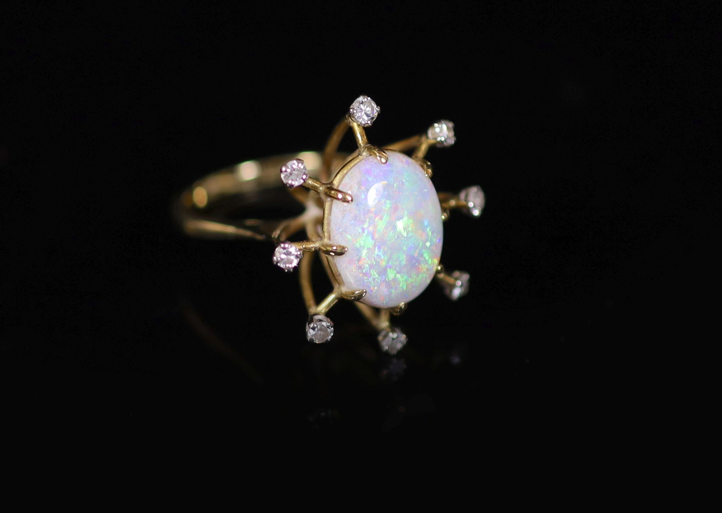 An 18ct gold, single stone oval white opal and eight stone diamond set modernist ring